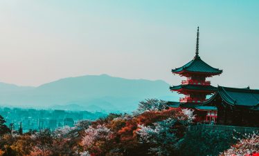 Scenic view of Kiyomizu-dera Temple with cherry blossoms in Kyoto, Japan, capturing traditional Japanese architecture at twilight.