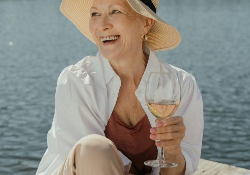 Senior woman enjoying a summer day on a pier with a glass of wine.